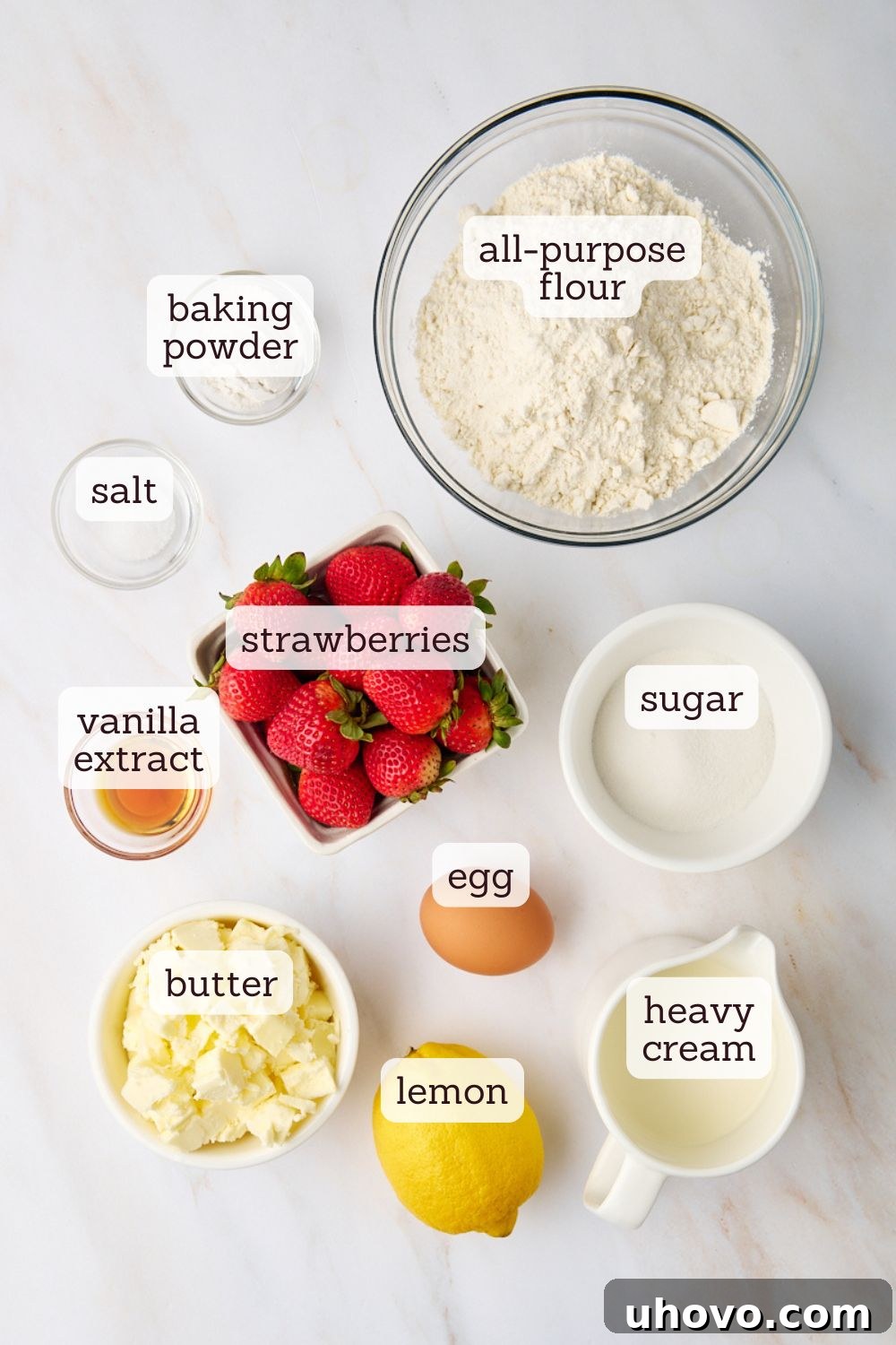 An overhead shot showcasing the key ingredients artfully arranged for strawberry shortcake preparation, including flour, sugar, butter, and fresh strawberries, hinting at the delightful creation to come.