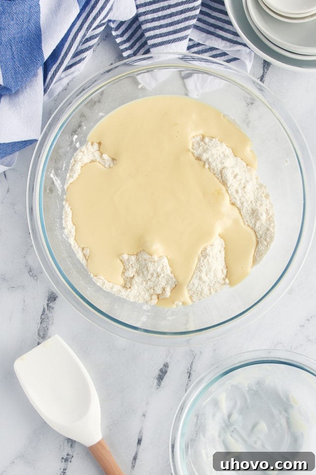 The smooth yogurt mixture being poured into the dry flour-butter mixture, demonstrating the next step in creating the cake batter.