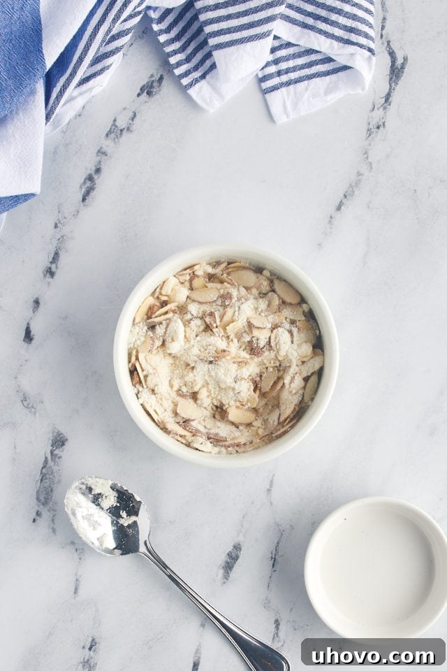 The completed almond crumble mixture in a small bowl, showcasing its readiness to be sprinkled over the cake.