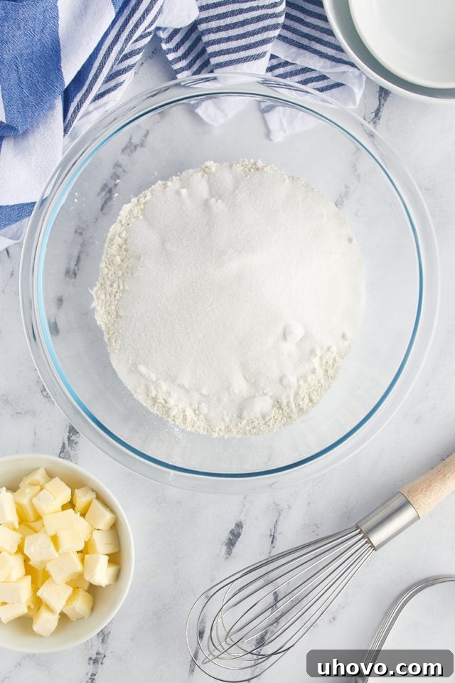 Overhead shot of all-purpose flour and granulated sugar whisked together in a large mixing bowl, forming the base of the cake batter.