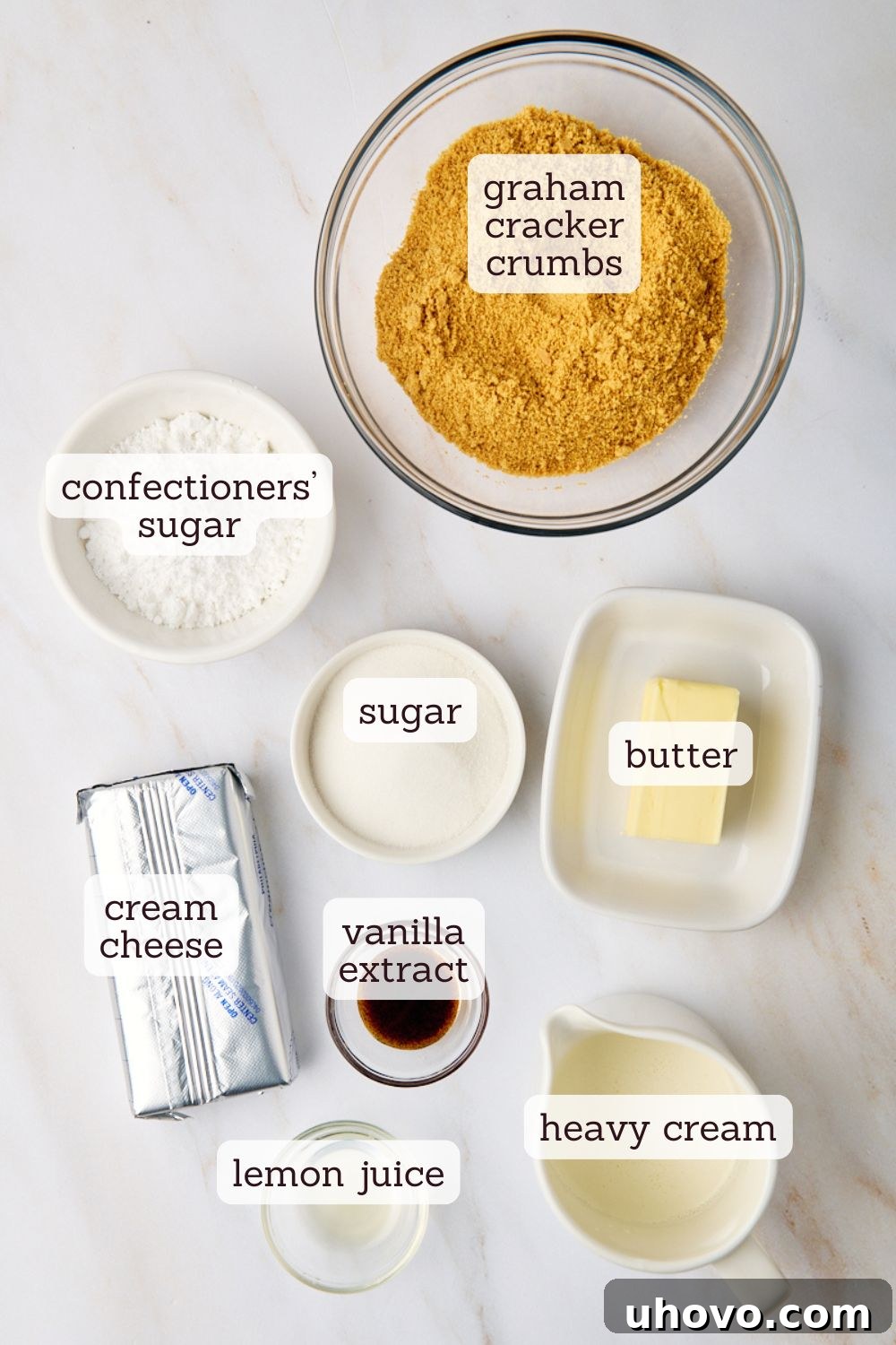 An overhead view showcasing all the essential ingredients laid out for making mini no-bake cheesecakes, including graham crackers, cream cheese, sugar, vanilla, butter, and heavy cream.