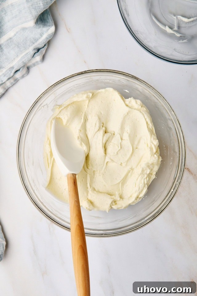 An overhead view of the completed no-bake cheesecake filling in a glass mixing bowl, showcasing its smooth, creamy, and airy consistency, ready for assembly.