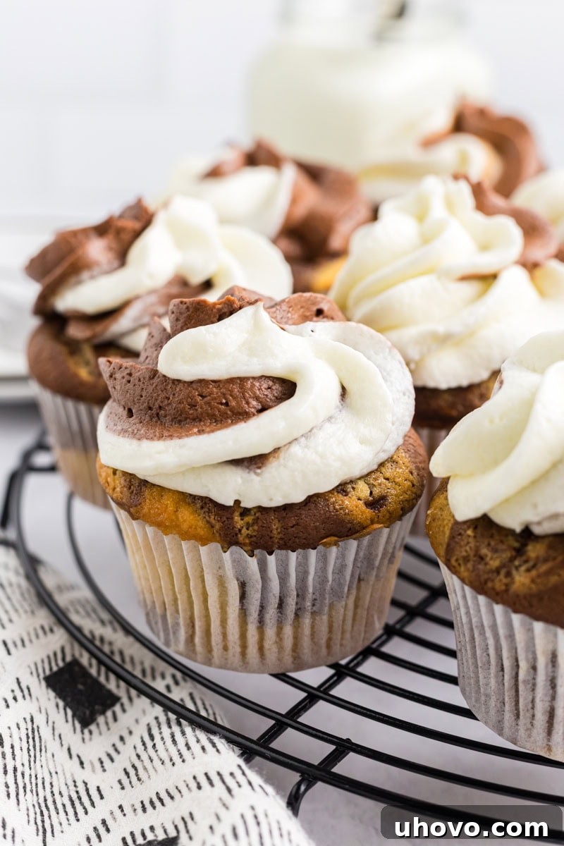 A collection of beautifully frosted marble cupcakes arranged on a wire rack, showcasing their elegant two-tone frosting swirls and readiness for enjoyment. This image emphasizes their fresh appeal.