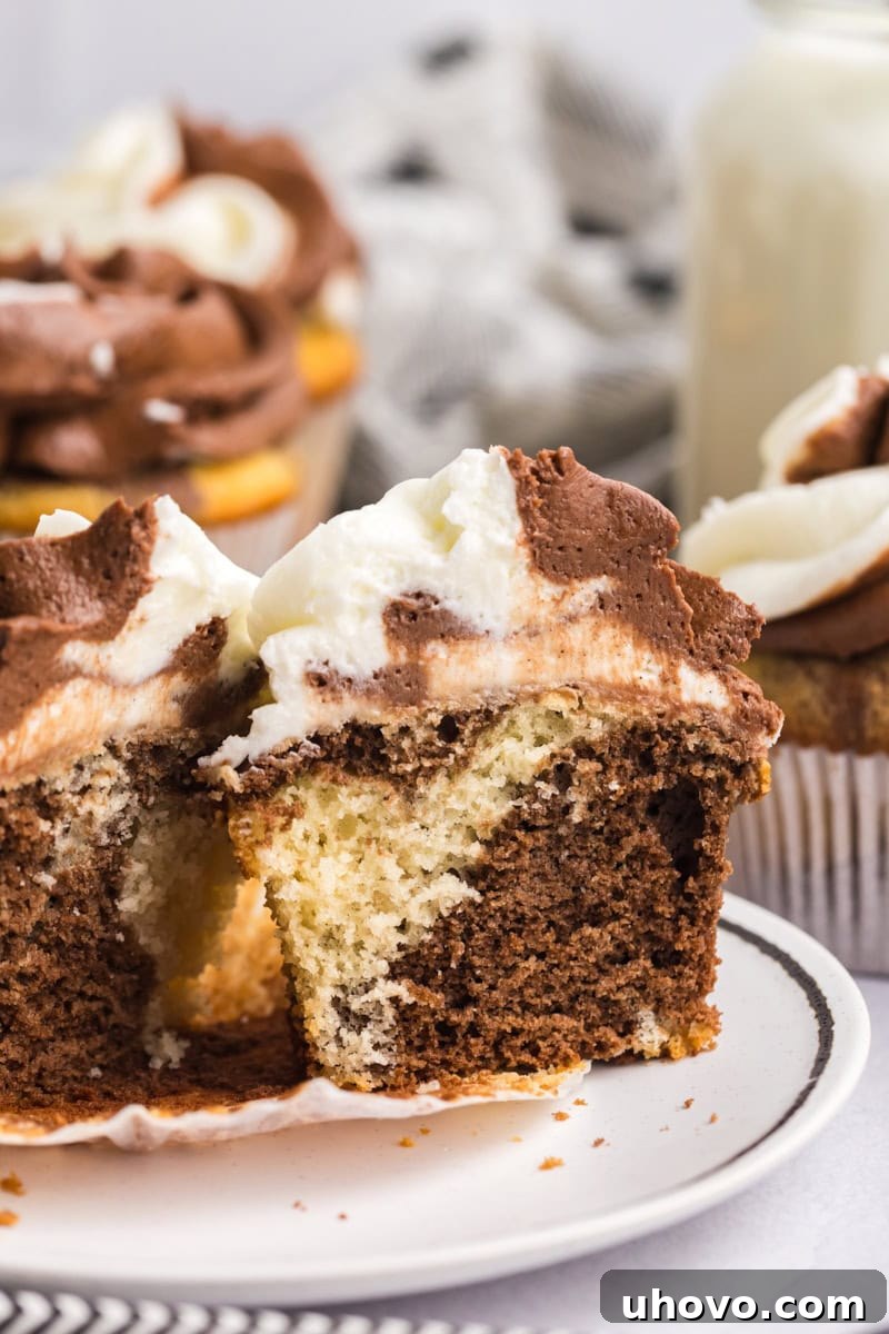 A marble cupcake expertly cut in half, revealing the intricate and delicate marbling effect of the chocolate and vanilla cake layers within. This close-up highlights the perfect swirl.