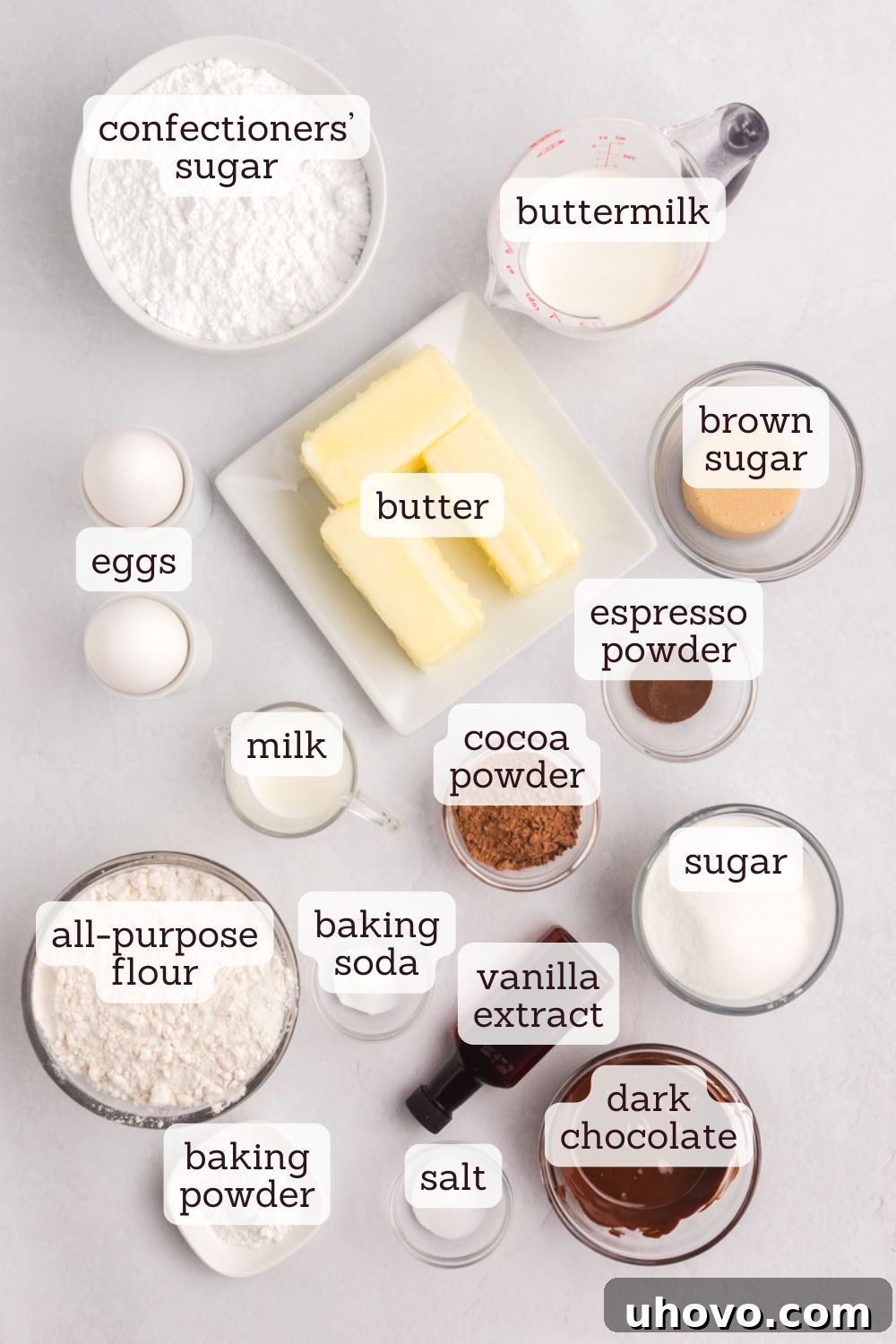 An overhead view of various marble cupcake ingredients laid out neatly on a wooden surface, including flour, sugar, butter, eggs, milk, and chocolate. This image highlights the fresh components used in the recipe.
