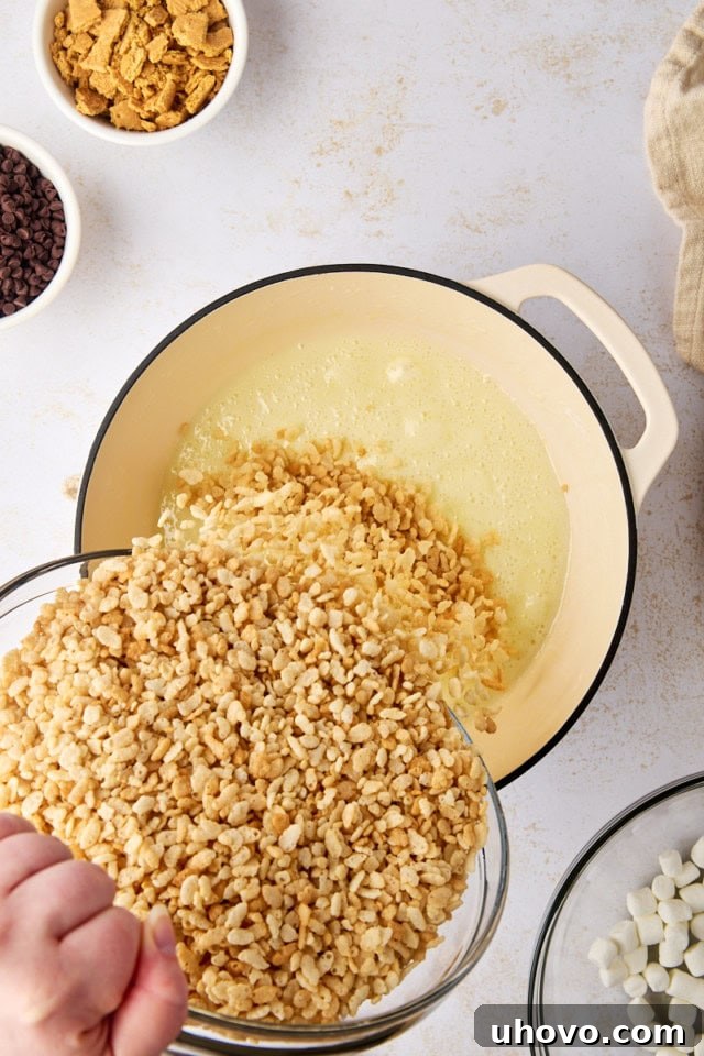overhead view of rice cereal being poured into melted butter and marshmallow mixture