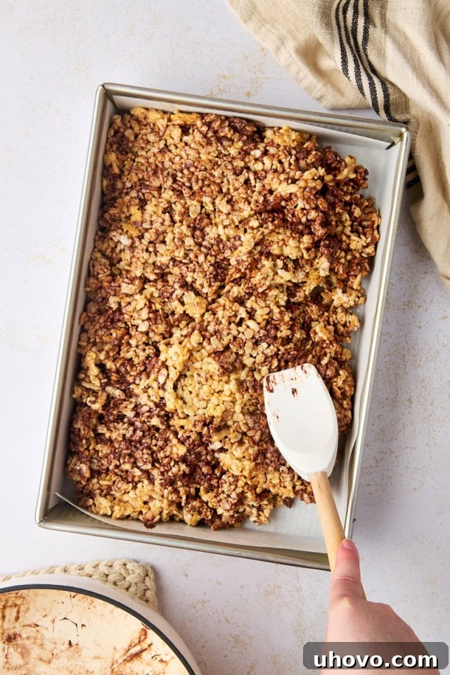 overhead view of s'mores rice crispy treats being spread in a 9x13 pan