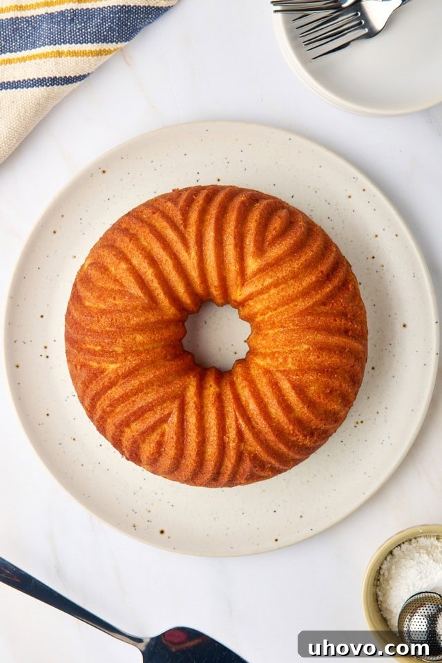 An overhead view of the beautifully baked cornmeal pound cake, inverted and perfectly presented on a pristine white cake plate, ready for slicing.