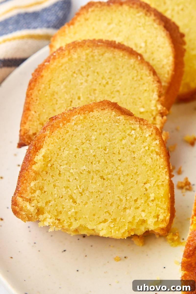 Several delectable slices of golden cornmeal pound cake arranged enticingly on a white cake plate, highlighting its unique texture.