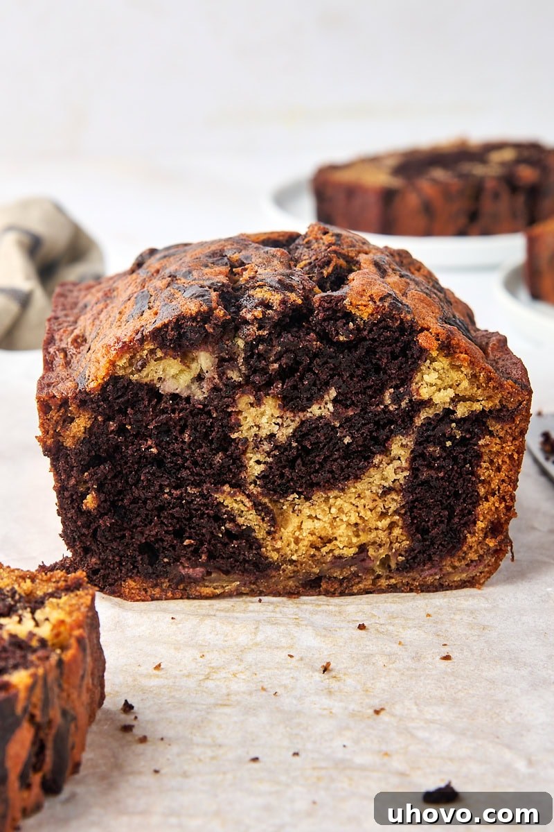 A large piece of marbled chocolate banana bread on parchment paper, with a rustic, inviting appearance, hinting at its delicious flavor.