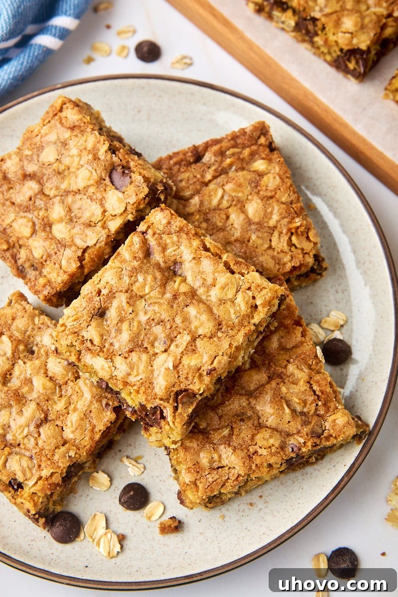 An inviting overhead view of several oatmeal cookie bars neatly stacked on a white plate, showcasing their soft texture and chocolate chips.