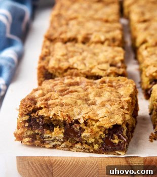 Perfectly baked oatmeal cookie bars on a parchment-covered cutting board, ready for slicing.