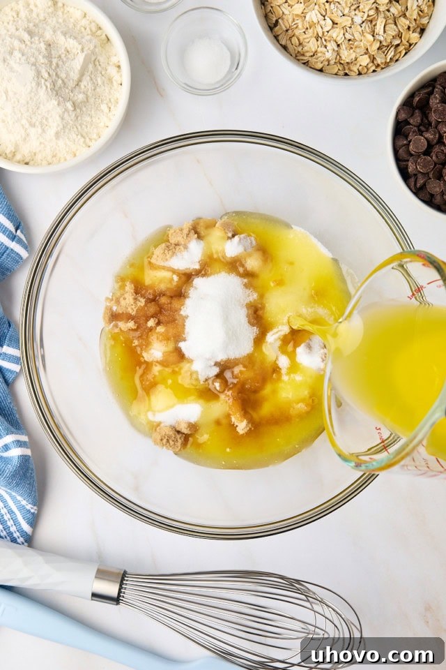 Overhead view of a glass mixing bowl containing melted butter, brown sugar, and granulated sugar, ready to be combined.