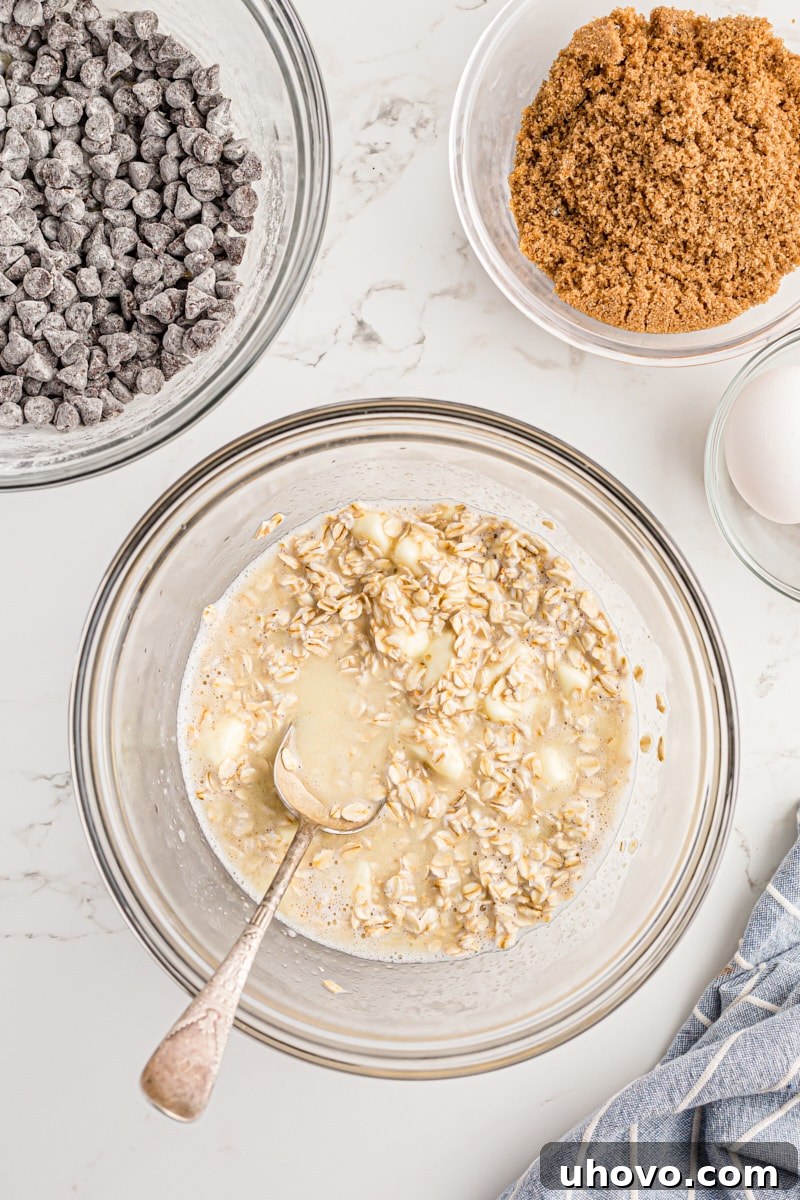 Overhead view of softened oats, butter, and water in a mixing bowl after stirring, showing the moist and melted consistency.