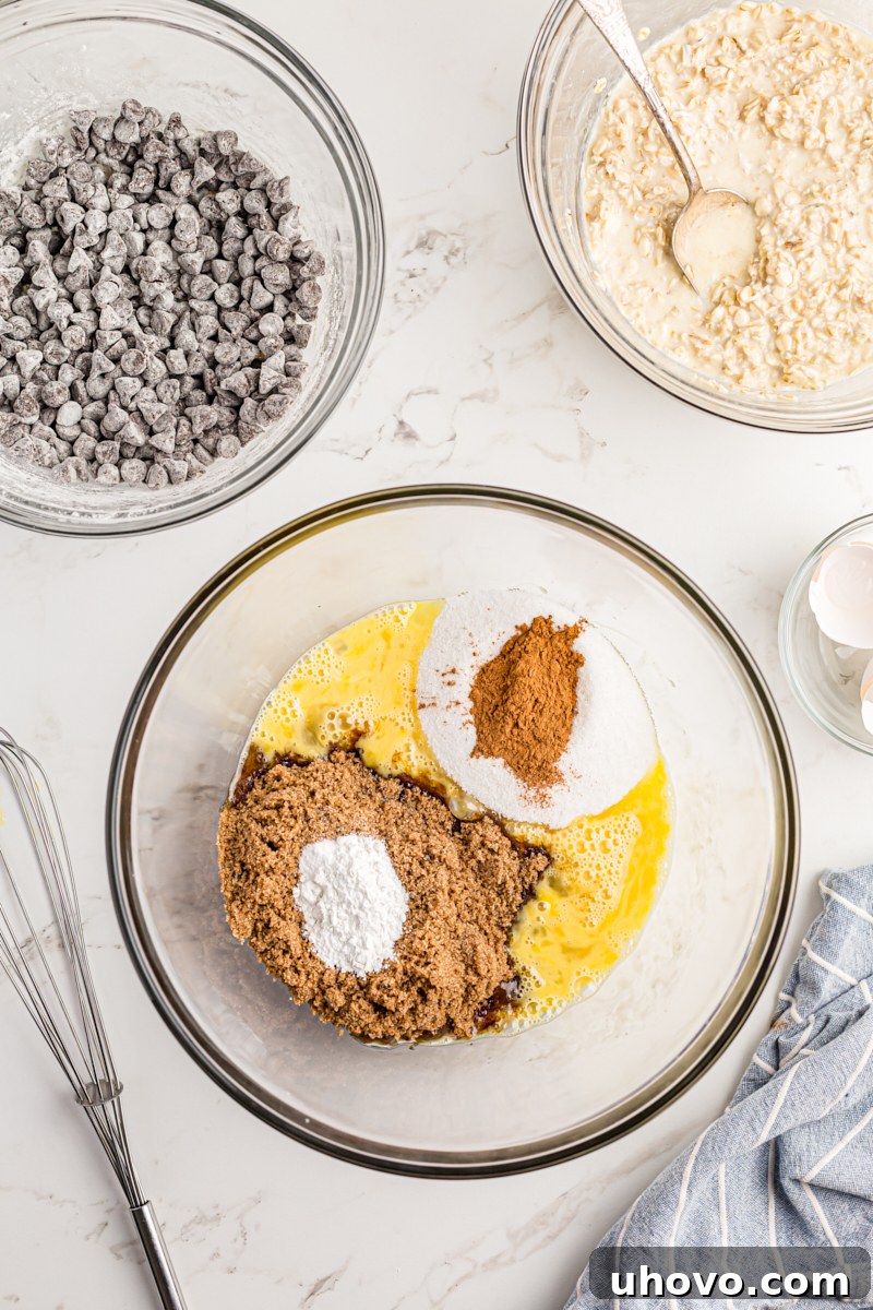 Overhead view of wet ingredients (eggs, sugars, etc.) being whisked in a mixing bowl for the cake batter.