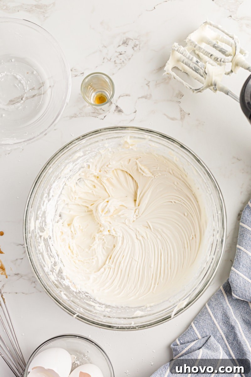 Overhead view of the finished, smooth cream cheese frosting in a clear glass mixing bowl.