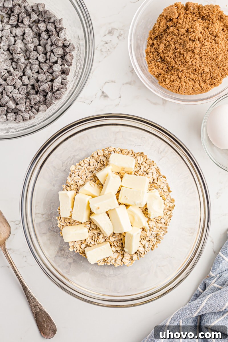 Overhead view of butter and rolled oats in a large mixing bowl.