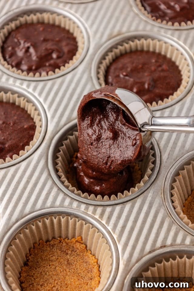 overhead view of chocolate cupcake batter being portioned into a muffin pan