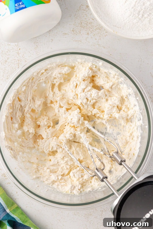 overhead view of beaten butter, marshmallow creme, and vanilla in a glass mixing bowl