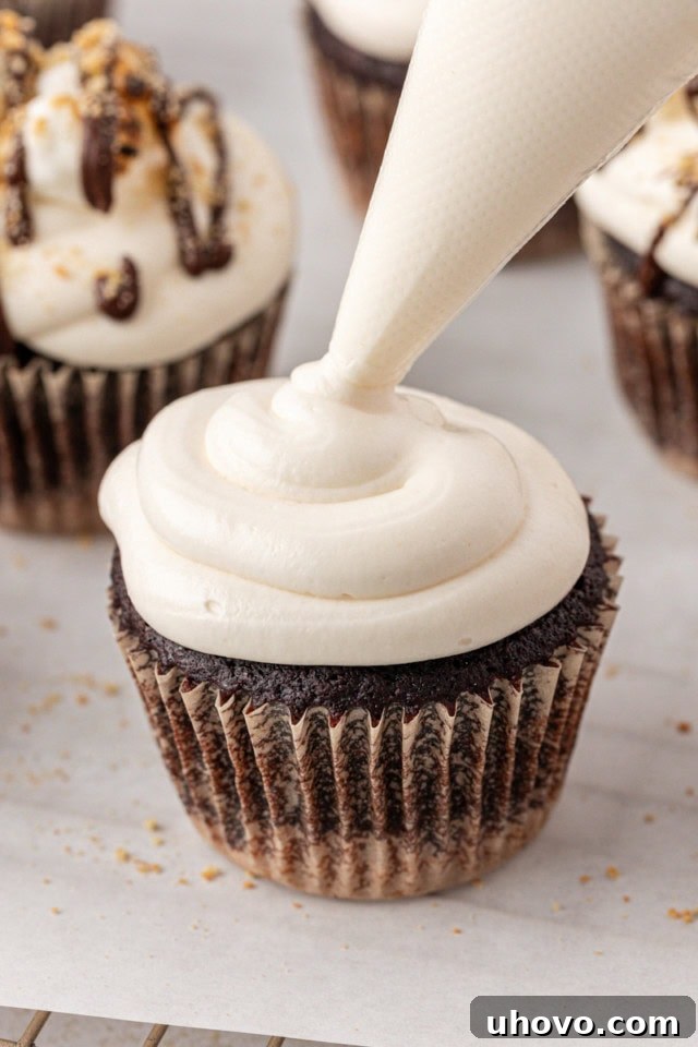 marshmallow frosting being piped onto a s'mores cupcake