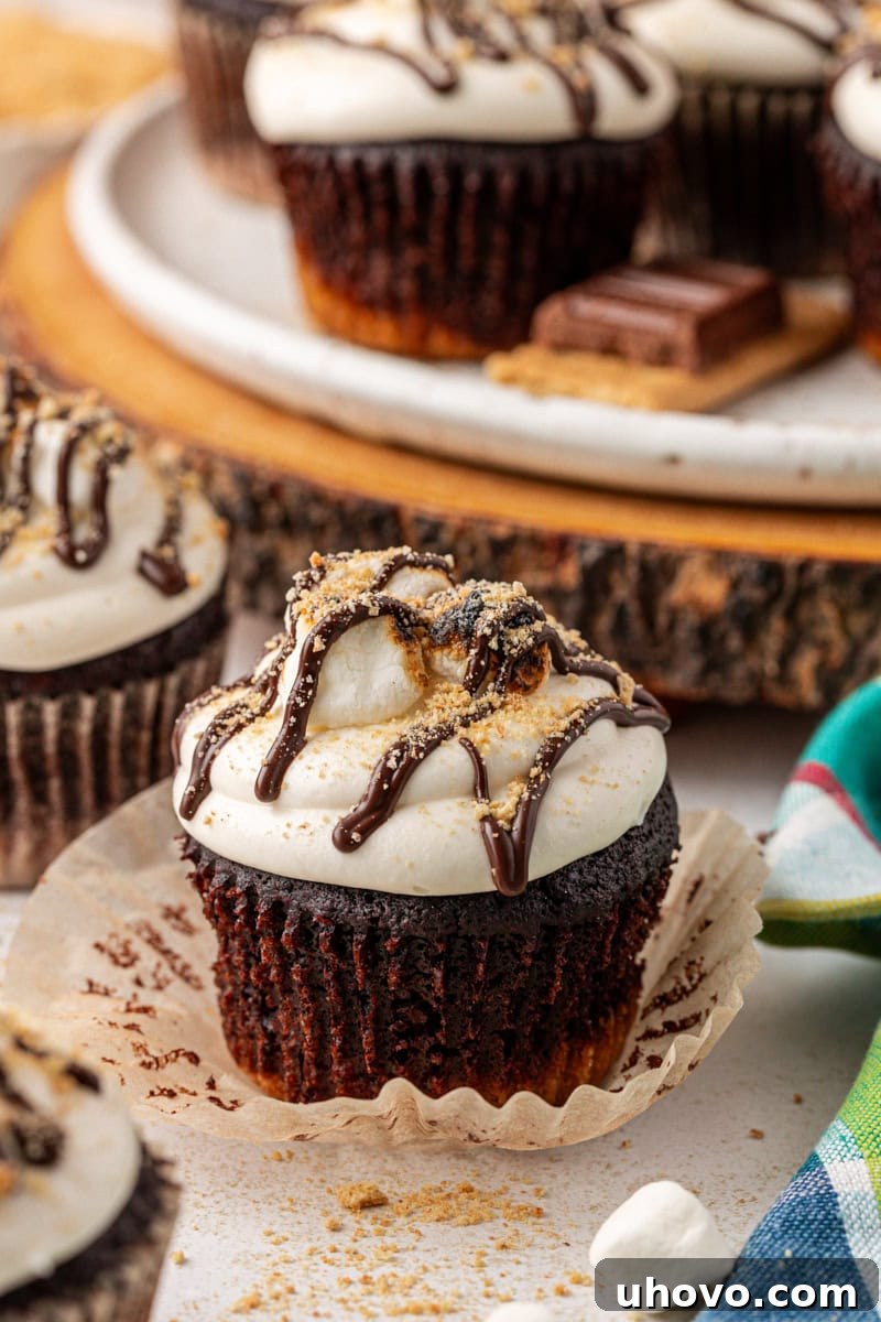 a s'mores cupcake sitting on its peeled-away wrapper with more cupcakes in the background