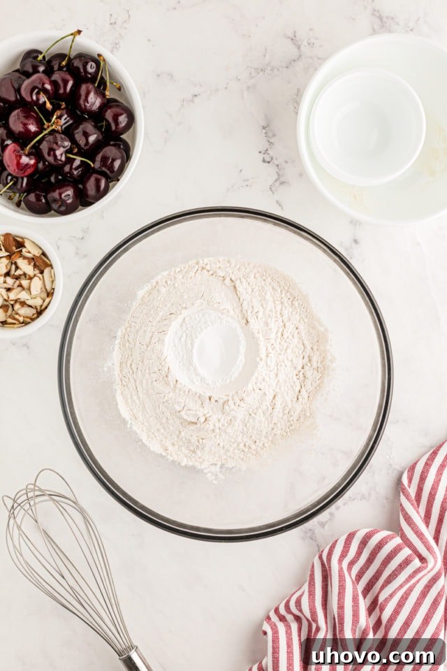 An overhead view of the dry ingredients—flour, baking powder, and salt—meticulously measured into a mixing bowl, ready to be whisked together for the cake batter.