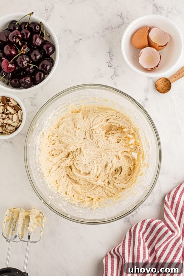 A close-up, overhead view of the fully mixed cake batter in a glass mixing bowl, showcasing its smooth, thick, and consistent texture, ready for the final assembly steps.