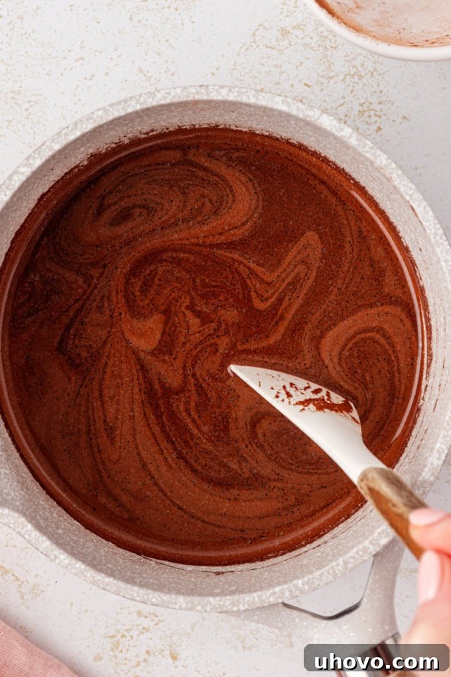 An overhead shot showing unsalted butter, cocoa powder, and water gently heating in a saucepan, forming the rich base for the chocolate cake.