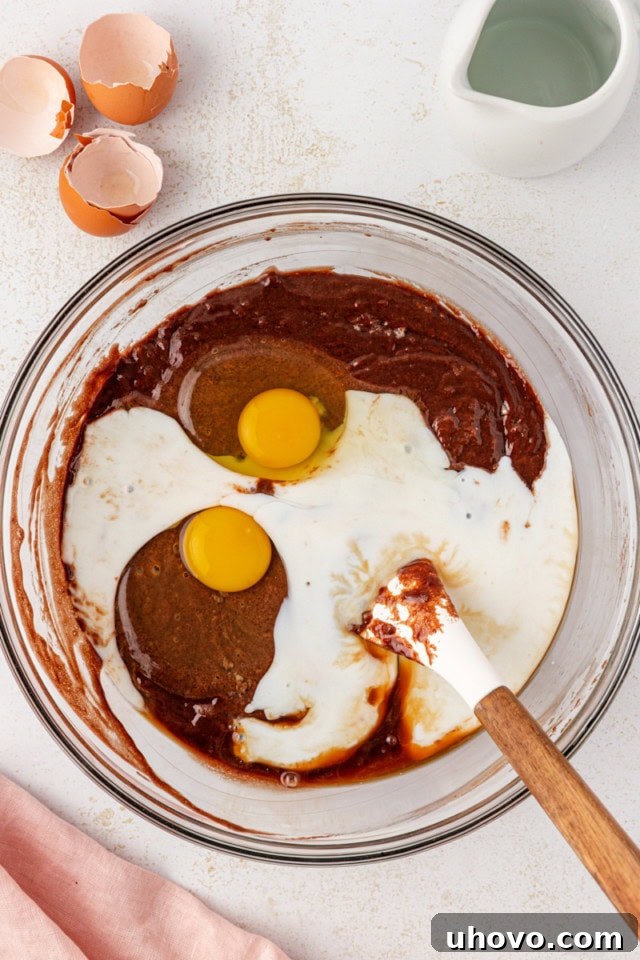 Eggs, creamy buttermilk, and fragrant vanilla extract are gently folded into the chocolate cake batter, ensuring a smooth and well-incorporated mixture.