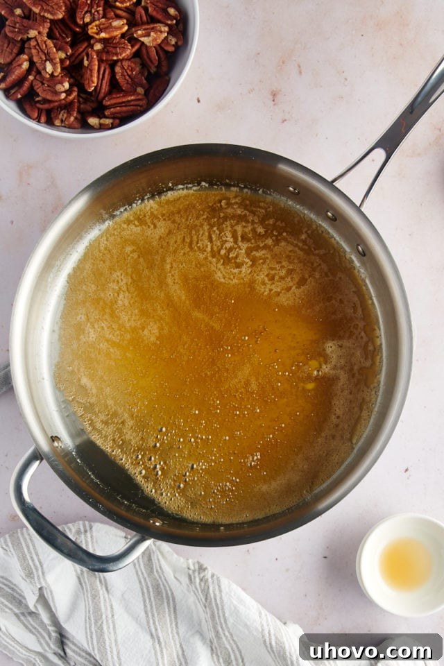 Overhead view of a shimmering glaze mixture bubbling in a large skillet, ready for pecans to be added.