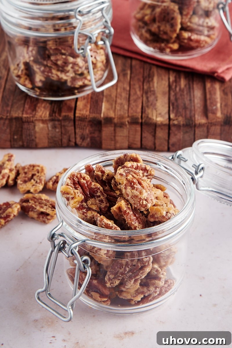 A clear glass jar filled with golden brown Glazed Pecans, ready for gifting or storage.