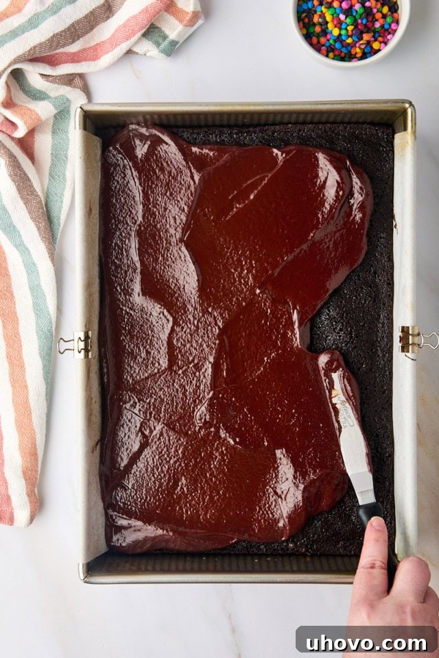 overhead view of ganache being spread over brownies in a 9x13 pan