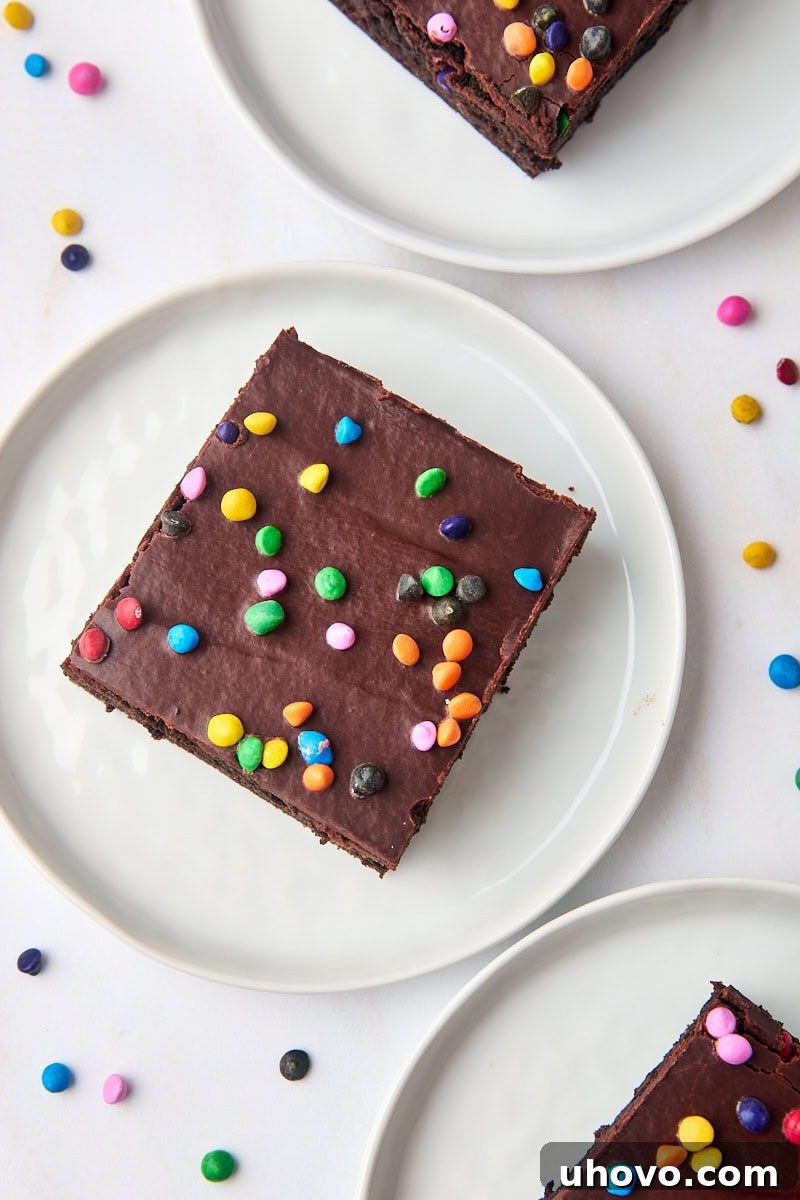 overhead view of a cosmic brownie on a white plate with two more brownies on plates partially visible