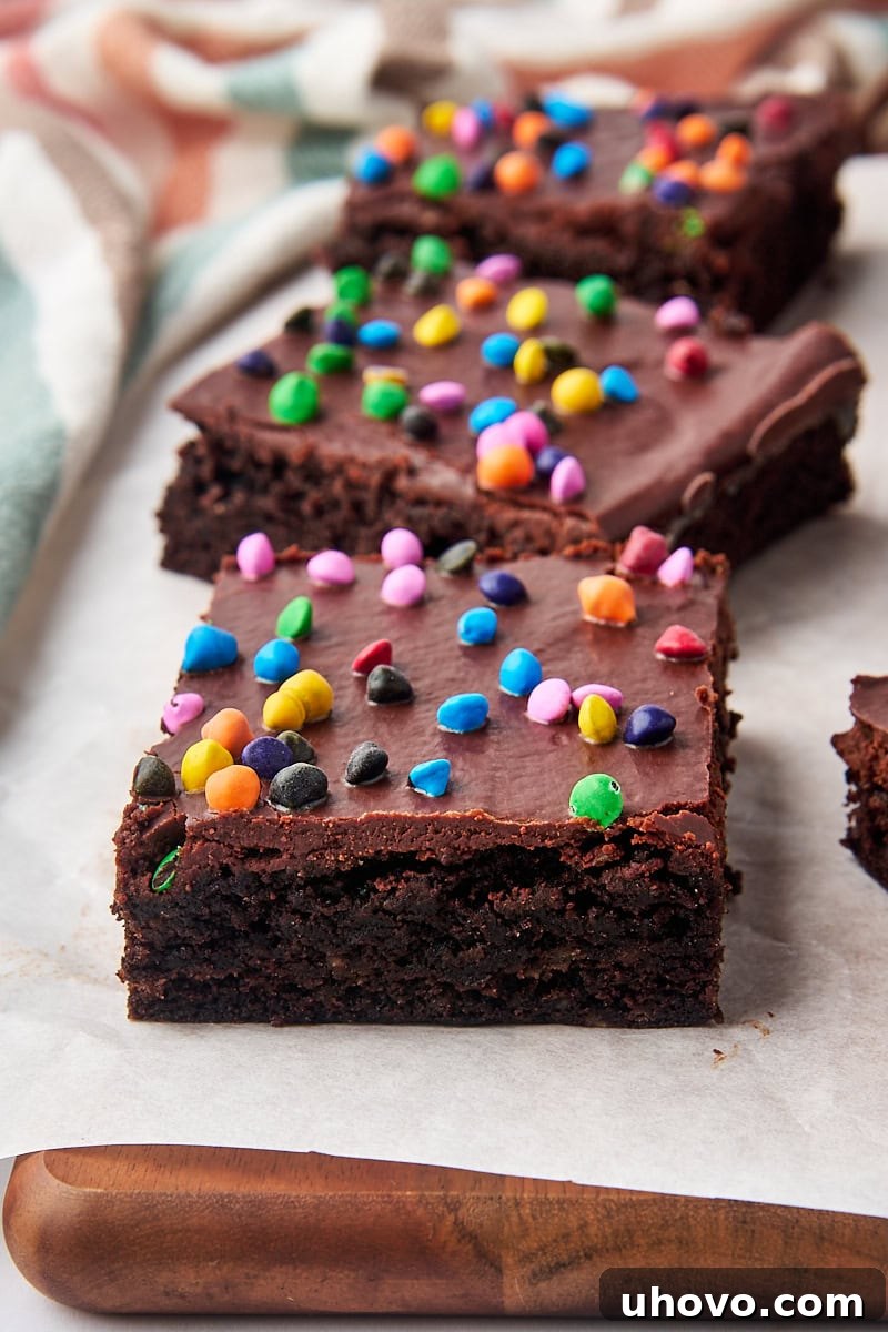 three cosmic brownies lined up on a parchment-covered wooden cutting board