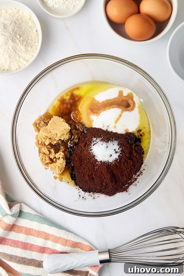 overhead view of melted butter, sugar, cocoa powder, salt, and vanilla in a glass mixing bowl