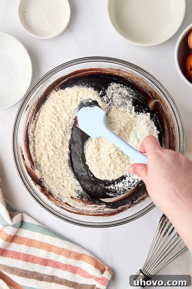 overhead view of flour and cornstarch being stirred into brownie batter