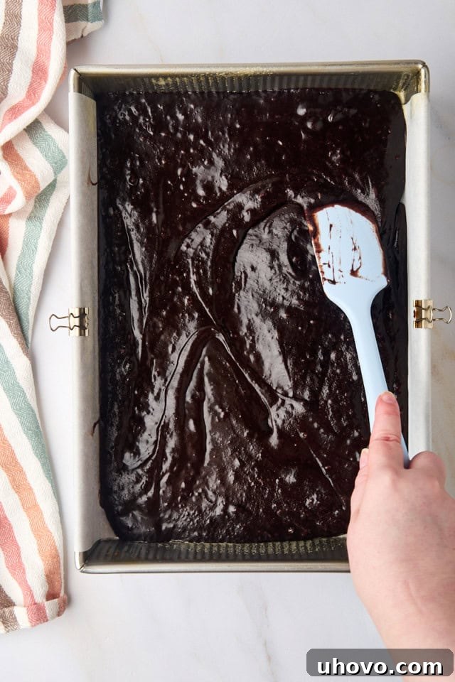 overhead view of brownie batter being spread in a 9x13 pan