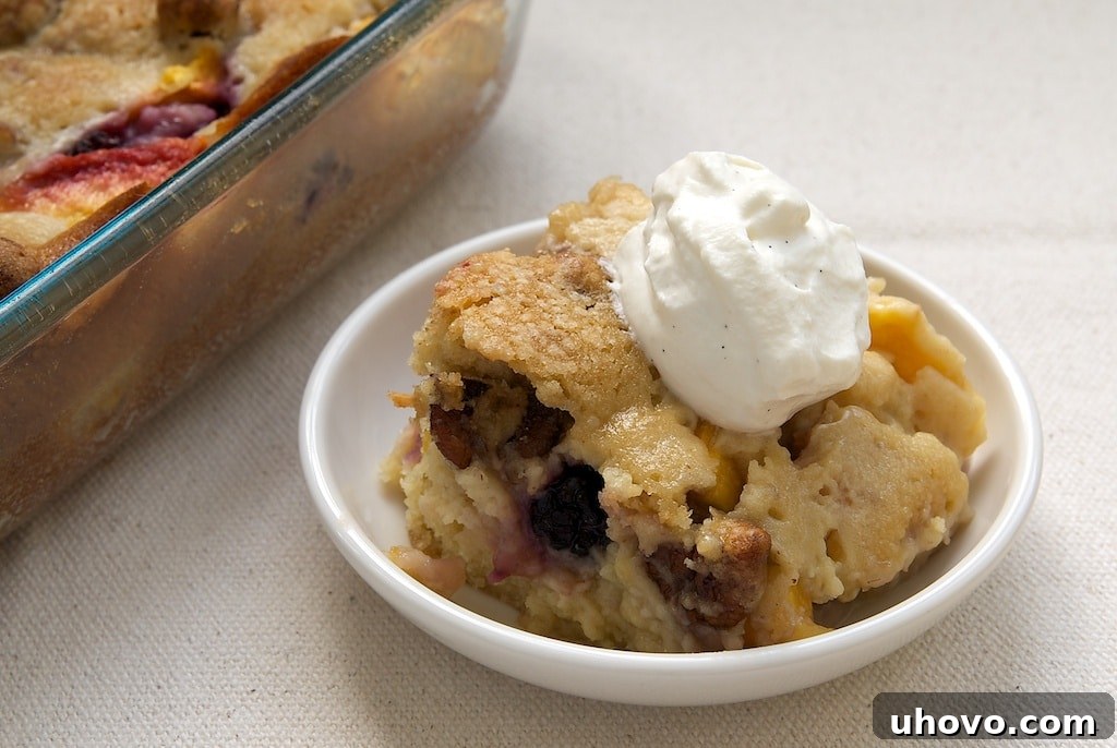 Blackberry Peach Cobbler garnished with a dollop of sweetened whipped cream and extra glazed pecans