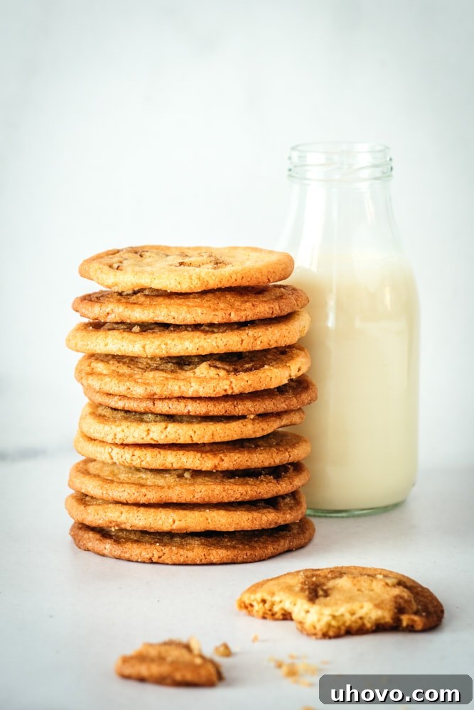 Stack of cinnamon roll cookies next to a glass milk bottle, suggesting a perfect pairing for a snack.
