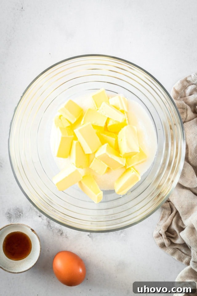 Softened butter and granulated sugar in a glass mixing bowl, ready to be creamed.