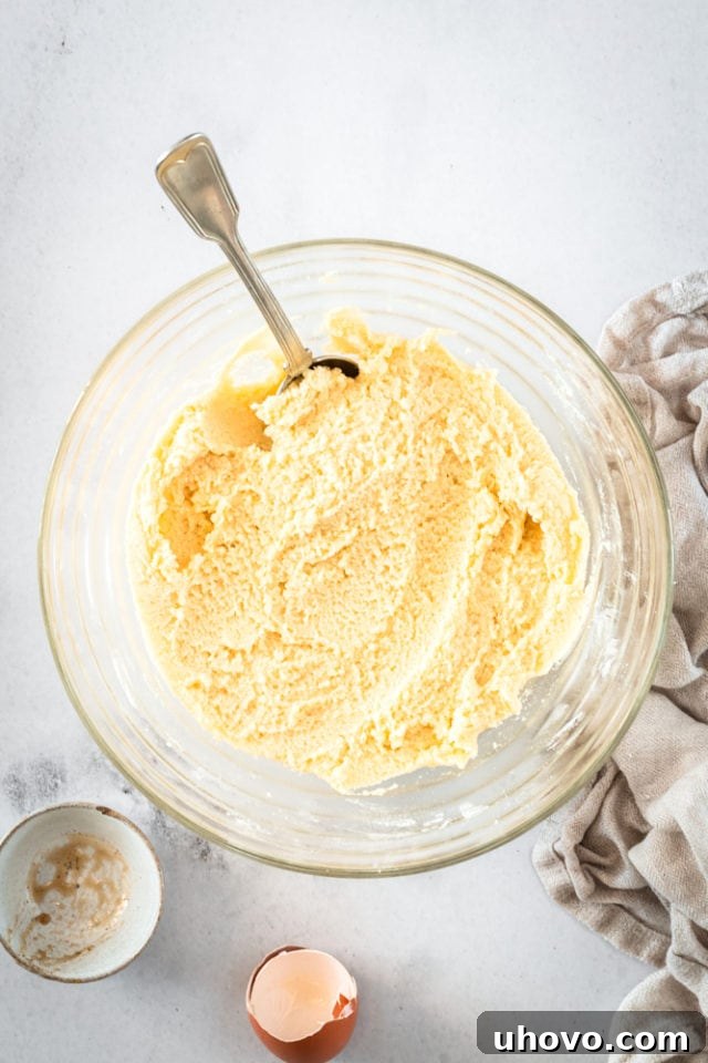 Sugar cookie dough in a glass bowl with a spoon, showing the consistency after flour has been added.