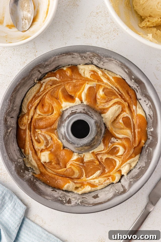 overhead view of caramel mixture swirled into vanilla cake batter in a Bundt pan