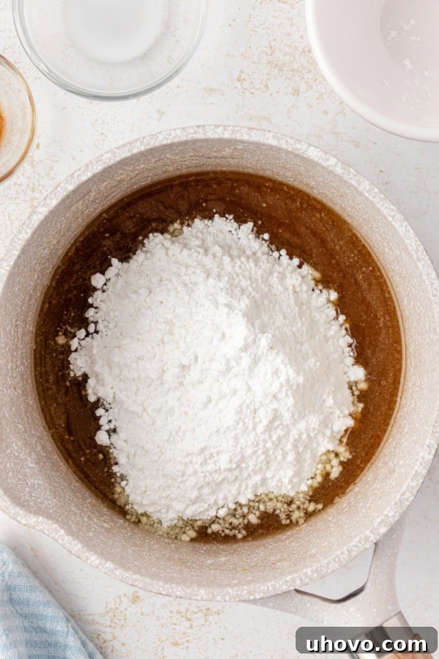 overhead view of confectioners' sugar added to caramel glaze mixture