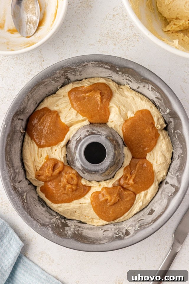 overhead view of caramel mixture spooned over vanilla cake batter in a Bundt pan