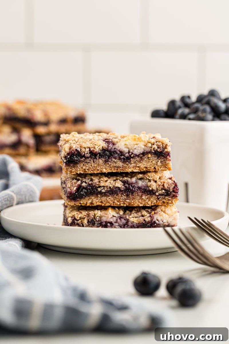 Stack of 3 blueberry jam cream cheese bars on white plate
