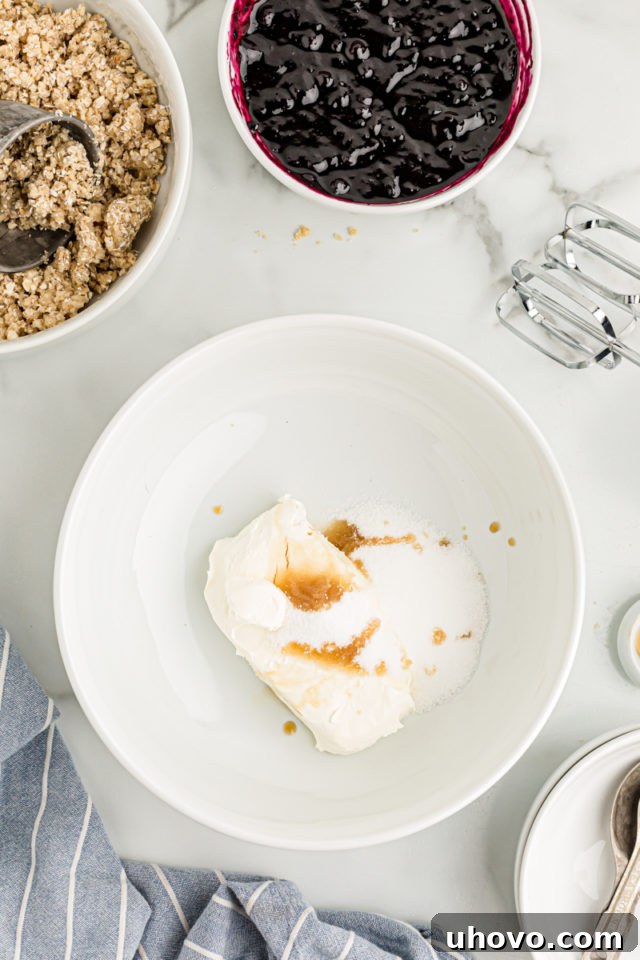 Overhead view of vanilla, sugar, and cream cheese in mixing bowl