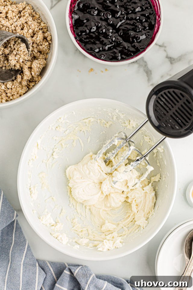 Overhead view of cream cheese filling in mixing bowl with hand mixer