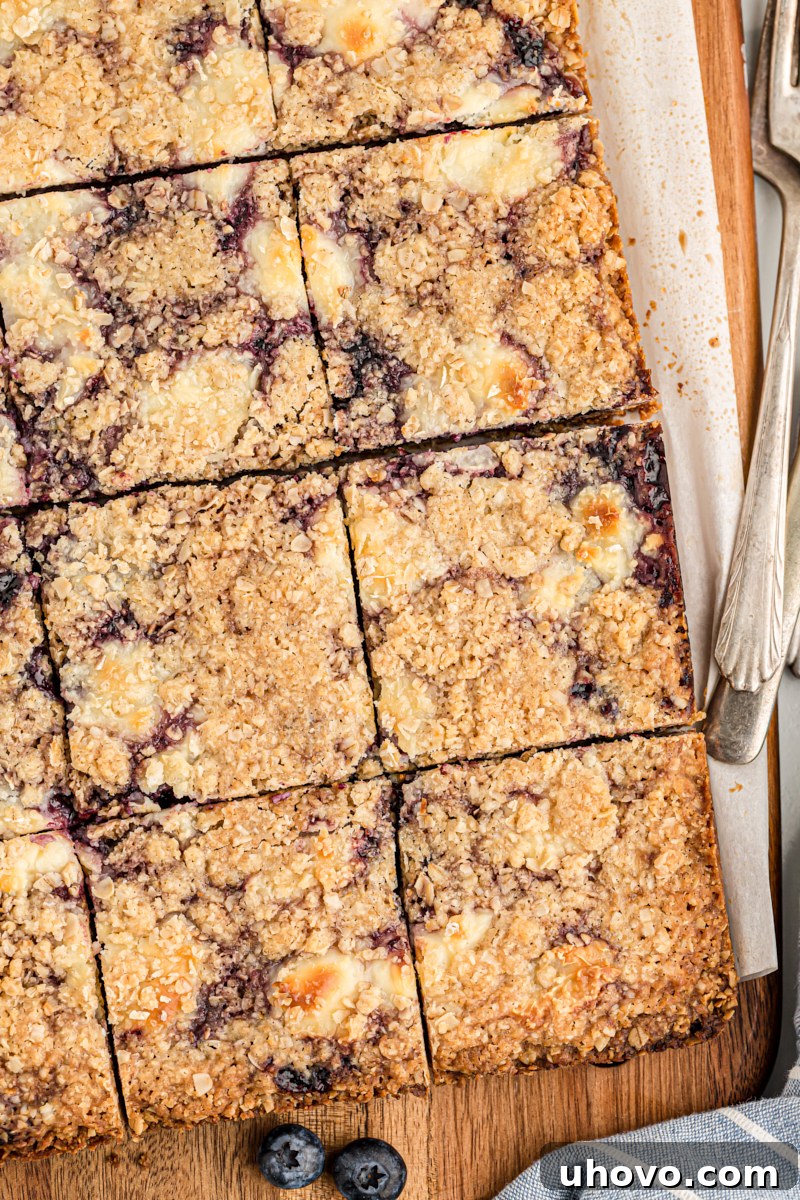 Overhead view of cut blueberry jam cream cheese bars on wood cutting board