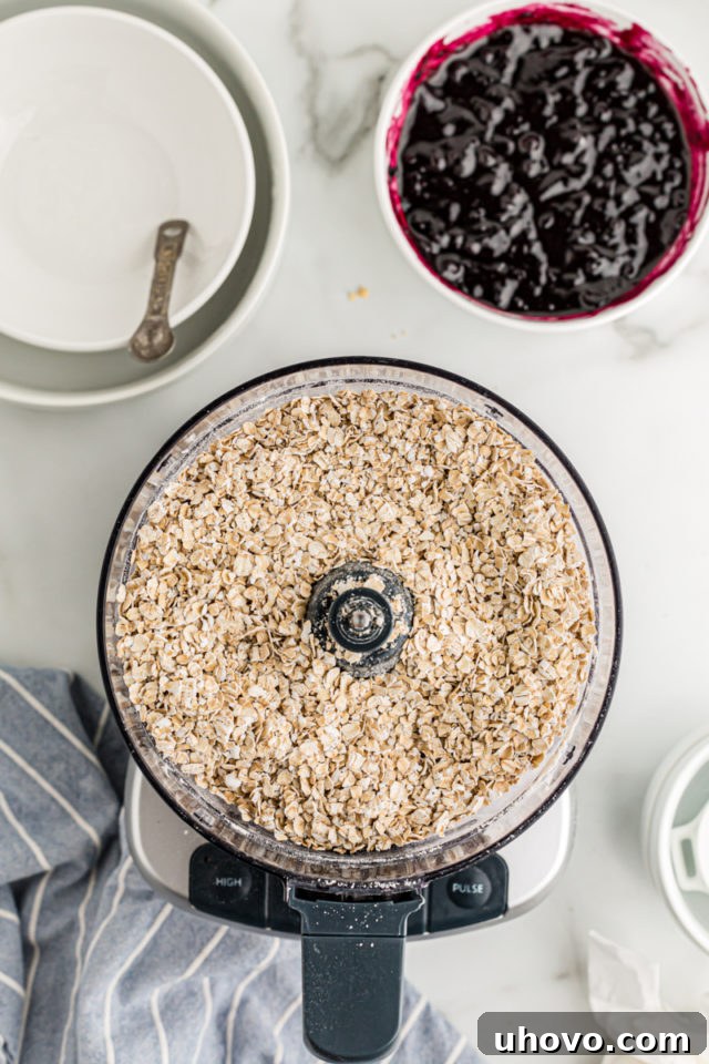 Overhead view of crust ingredients in food processor and blueberry jam in bowl