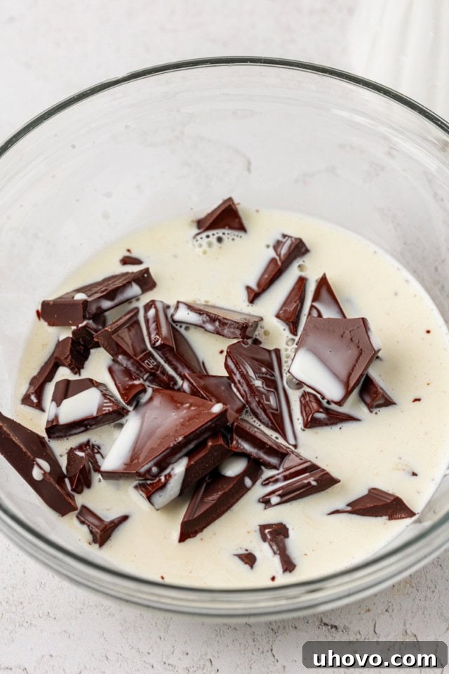 warmed cream poured over chopped chocolate in a glass bowl